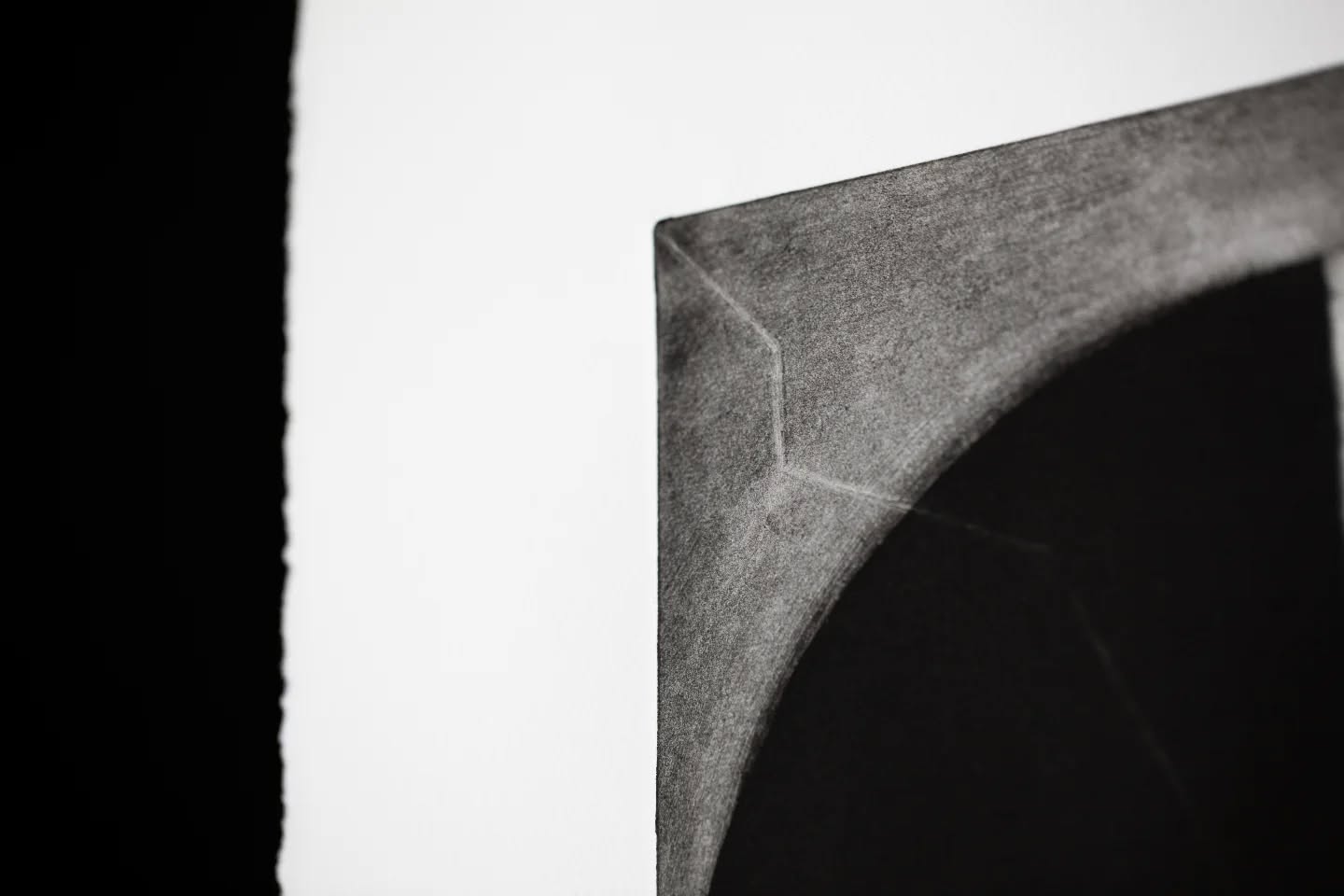 Close-up of a charcoal drawing showing a curved corner where an arc meets a straight edge, on white paper against black background.