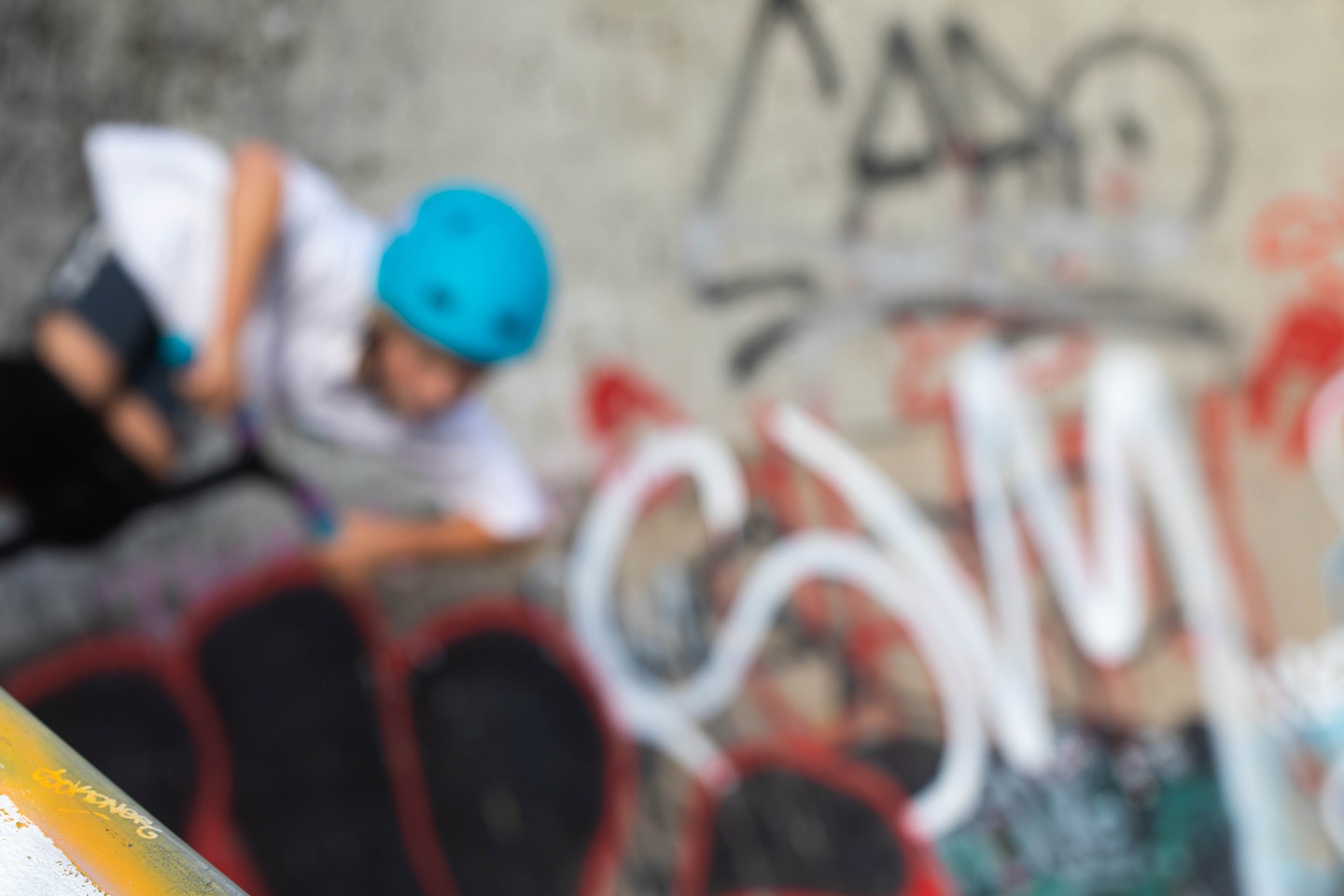 Blurred image of a person in a blue helmet skateboarding at a graffiti-covered skate park.