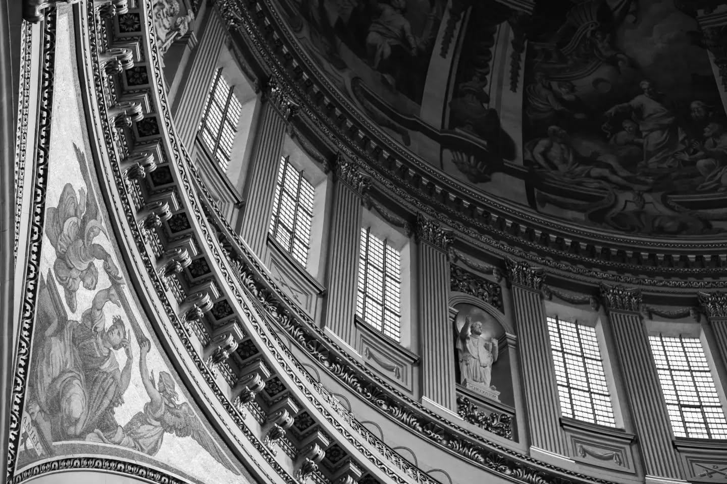 Black and white photo of a domed cathedral interior, showing curved walls with tall windows, fluted pilasters, and painted frescoes on the dome ceiling.