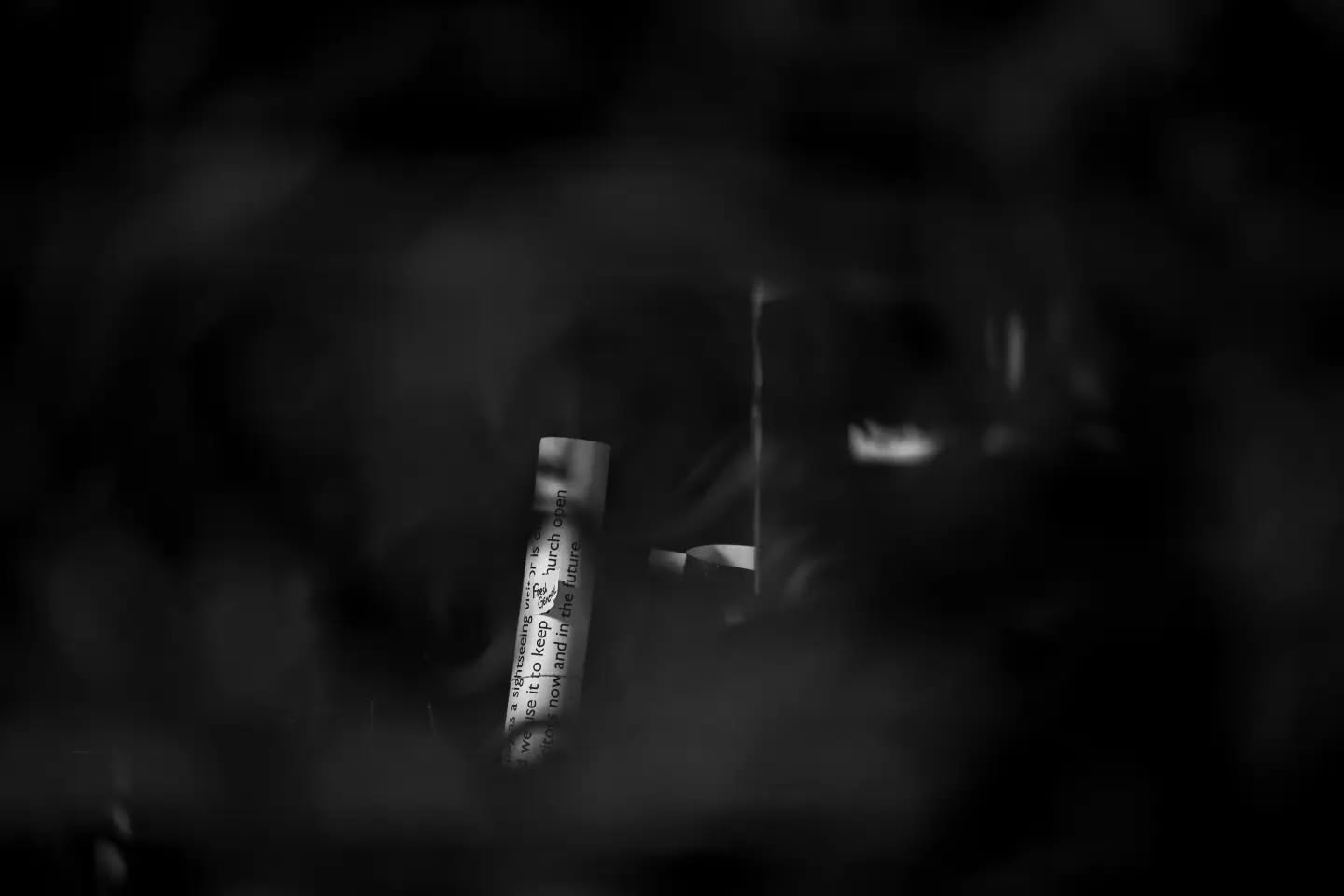 Black-and-white image of a curled paper strip with printed text about keeping a church open, set against a dark, blurred background.