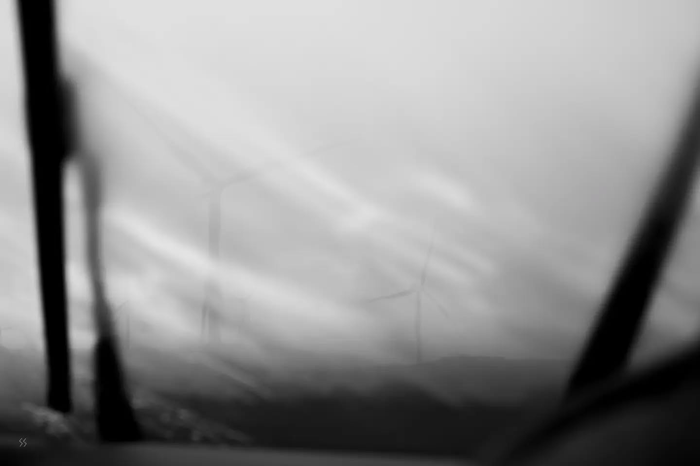 Black and white photograph featuring wind turbines, evoking a sublime, mythic atmosphere.
