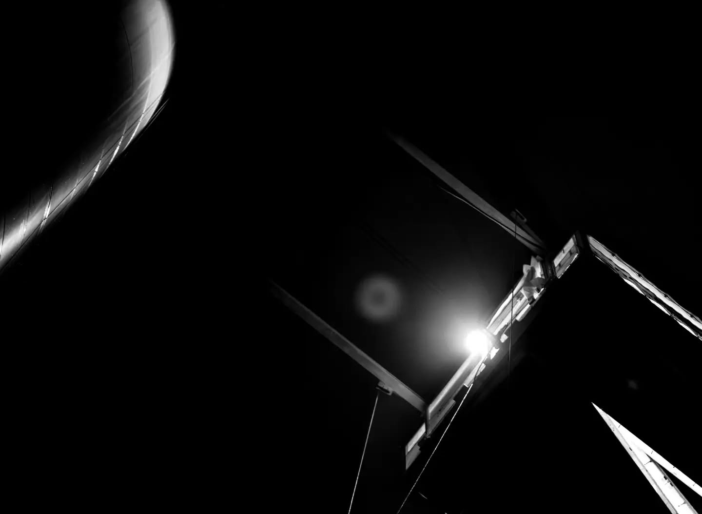 Black-and-white photograph of a wind turbine, viewed from below against the sky.