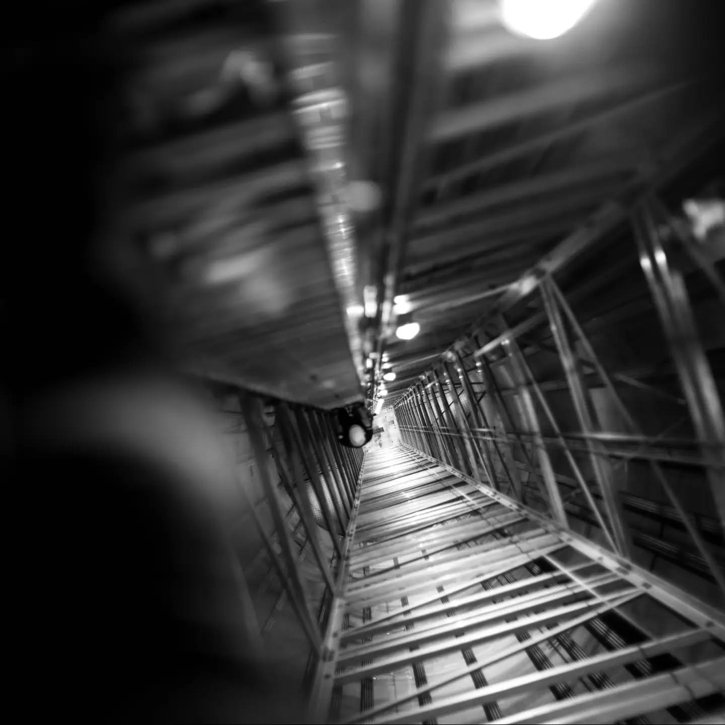 Black-and-white image of a spiraling staircase or ladder structure, evoking the Tower of Babel and Jacob's Ladder.