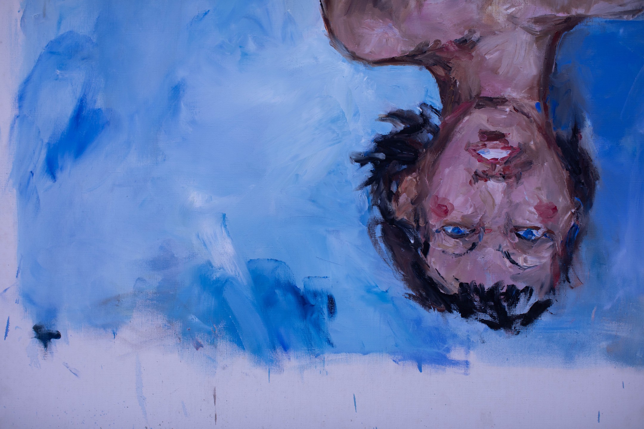 Oil painting, shown upside down, of two figures' heads against a blue background, one face with reddish marks on the forehead.